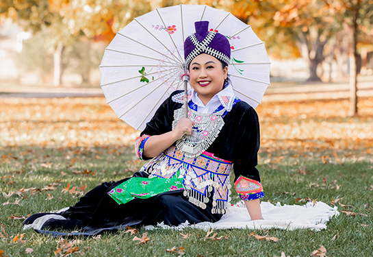 Portrait of a smiling woman with dark, long hair, wearing white shirt with black dots