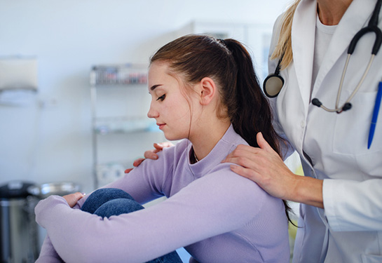 Doctor consoling unhappy teenage girl