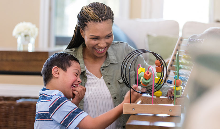 A young boy plays with an adult on an abacus-type toy.