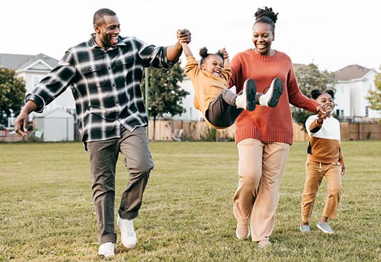 A mom, dad and two children play together outside