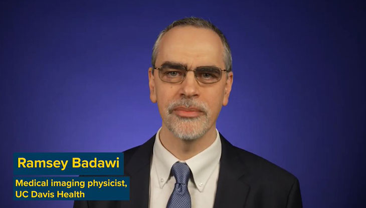 A man in a suit before a blue background.